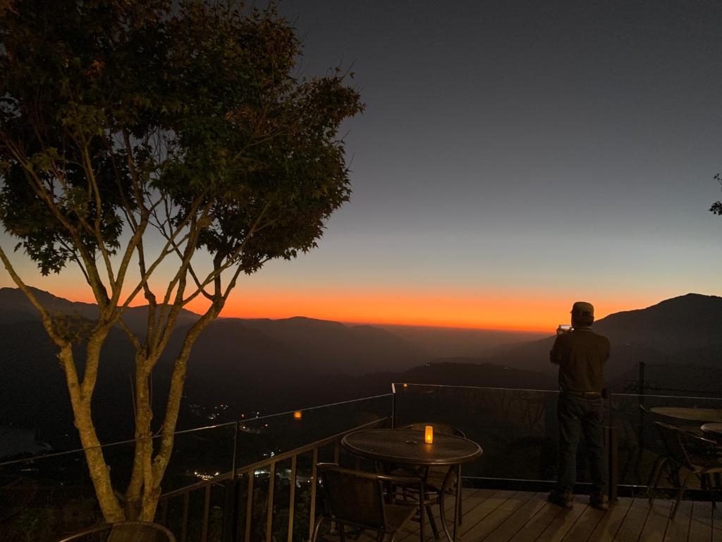 a man taking a picture of the sunset from a deck at Ming Ging Farm in Ren&#39;ai