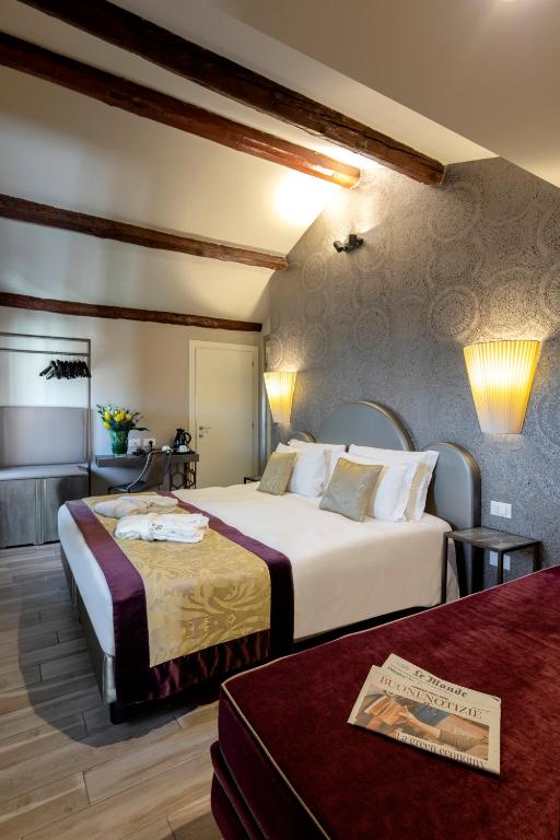 a hotel room with two beds and a table at Alle Guglie Boutique Hotel in Venice