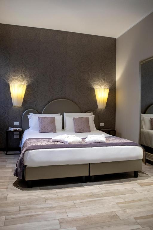 a bedroom with a large bed with two lamps on the wall at Alle Guglie Boutique Hotel in Venice