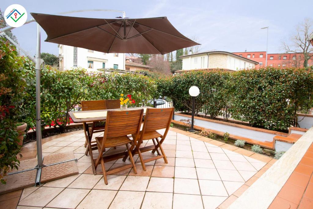 una mesa y sillas con una sombrilla en el patio en La Casina Del 5, en Villa Bertolli