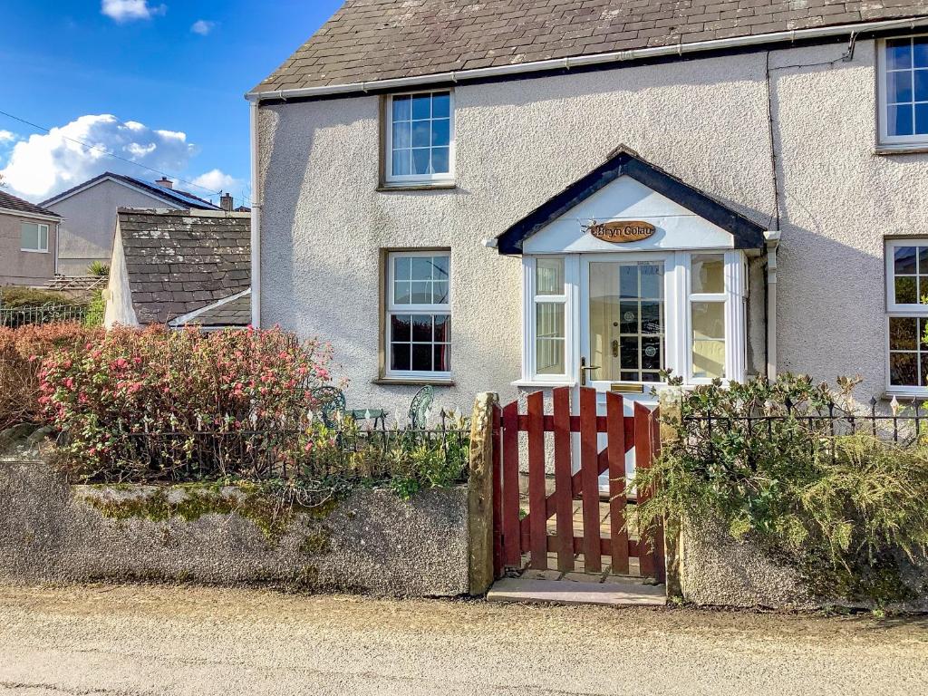 una casa con una puerta roja delante de ella en Bryn Golau en Llanfaethlu