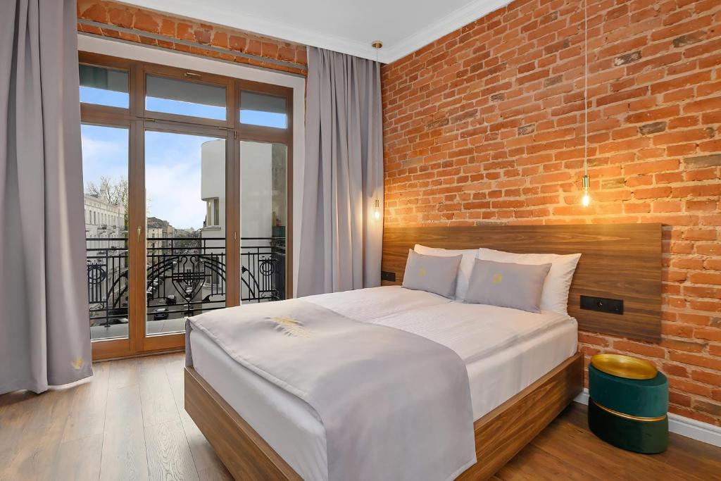 a bedroom with a large bed and a brick wall at Aparthotel Krzywa Kamienica in Łódź