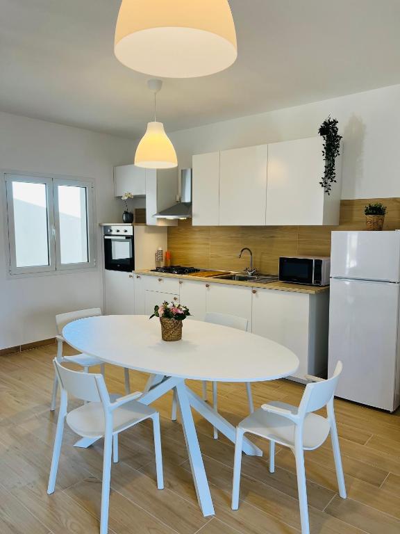 a white kitchen with a white table and chairs at Casa di Tinny in Barbusi