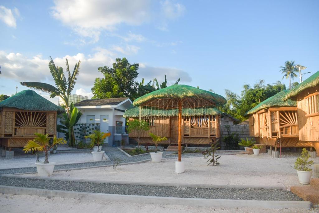 a group of houses with umbrellas and palm trees at GoOd Inn White Beach Moalboal in Cebu City