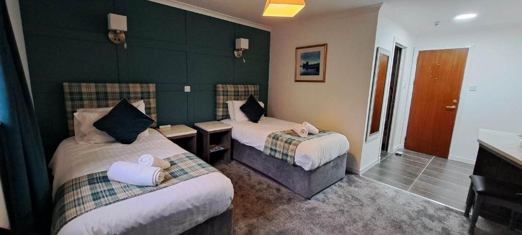 una habitación de hotel con 2 camas y una pared verde en MacDonald Hotel & Cabins en Kinlochleven