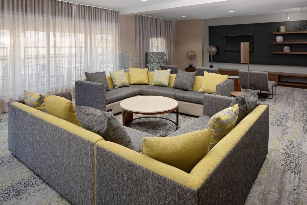 a living room with a large couch and yellow pillows at Courtyard by Marriott Houston Rice University in Houston