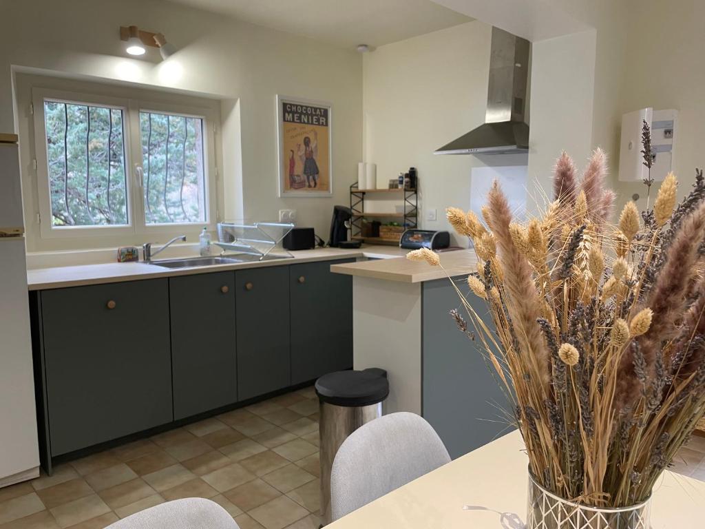 a kitchen with a table with a vase of flowers at T3 rénové esprit vintage, au coeur du Verdon in Montagnac