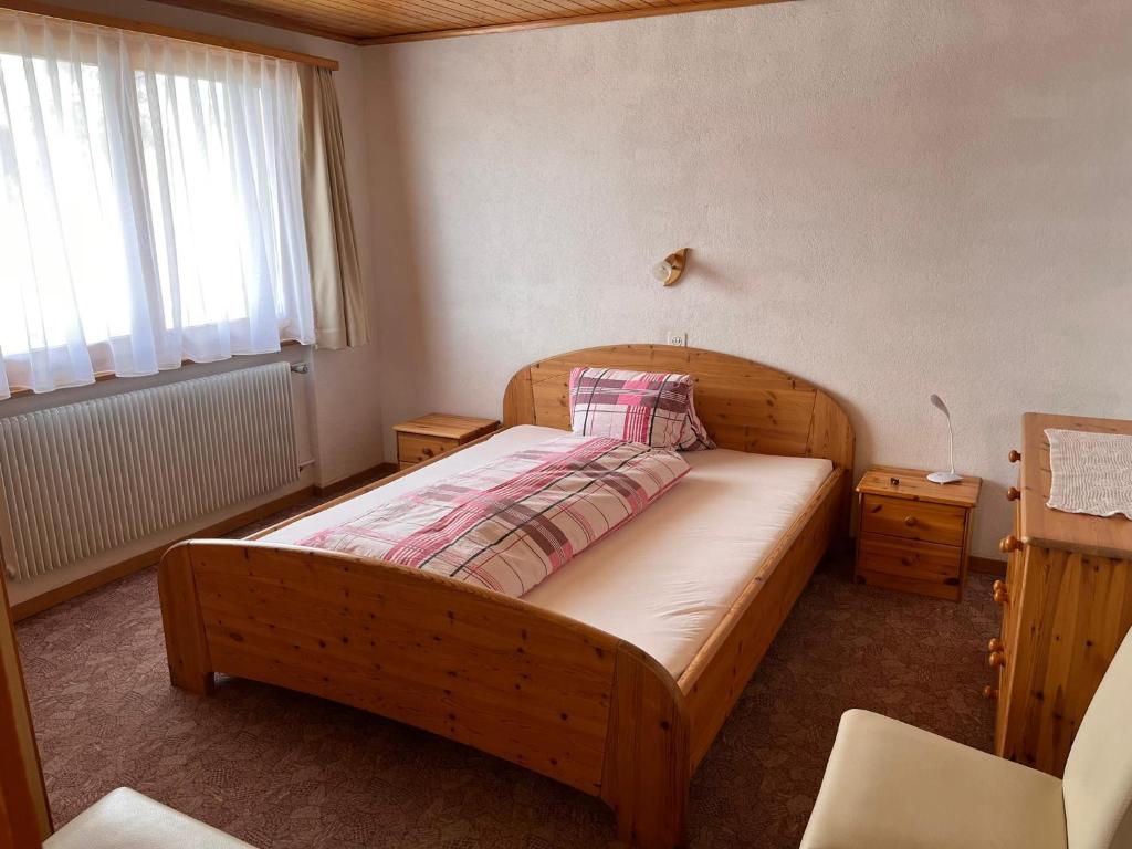 um quarto com uma cama de madeira e uma janela em Gaby em Grächen