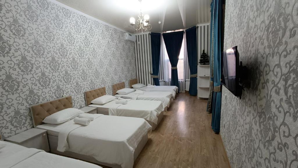 a row of white beds in a room at Aminabonu Hotel in Samarkand