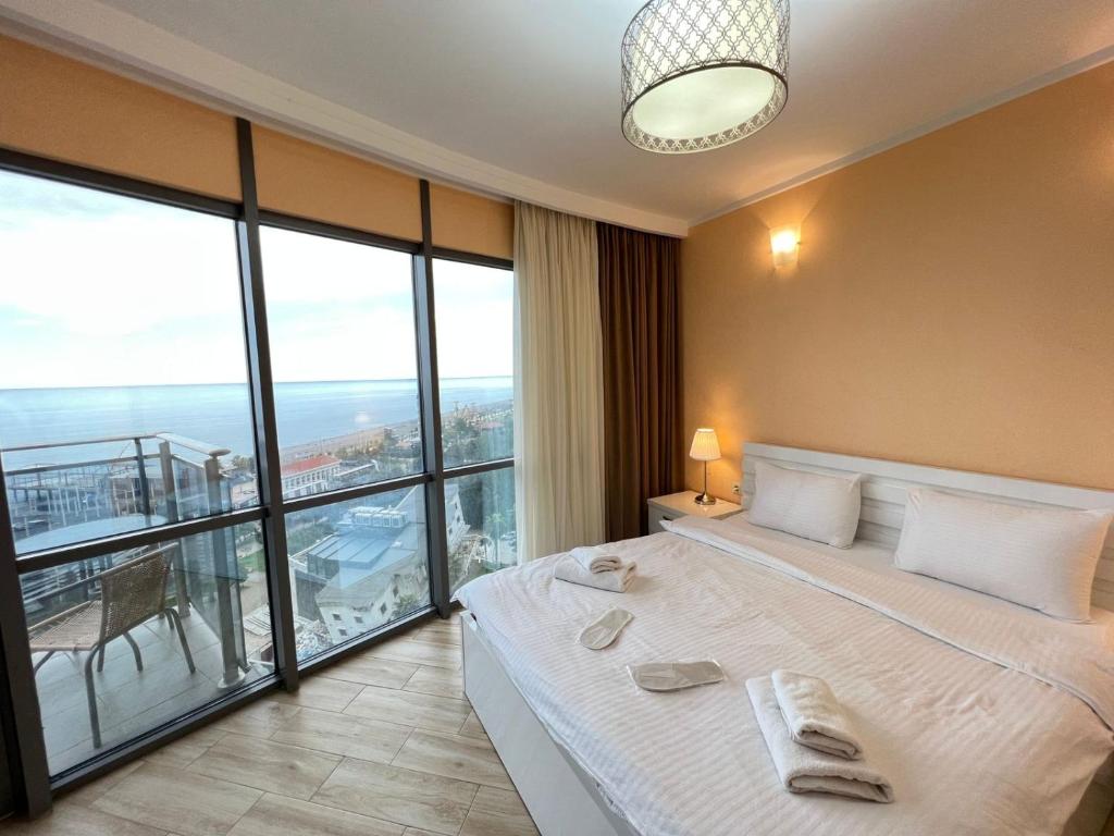 a bedroom with a large bed and a large window at Aparthotel Holiday Lux Batumi in Batumi