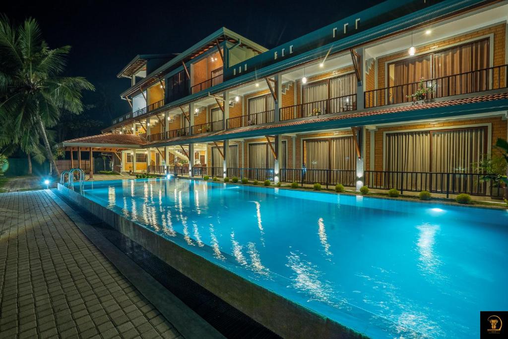 a swimming pool in front of a building at night at Anura's Elephant in Beruwala
