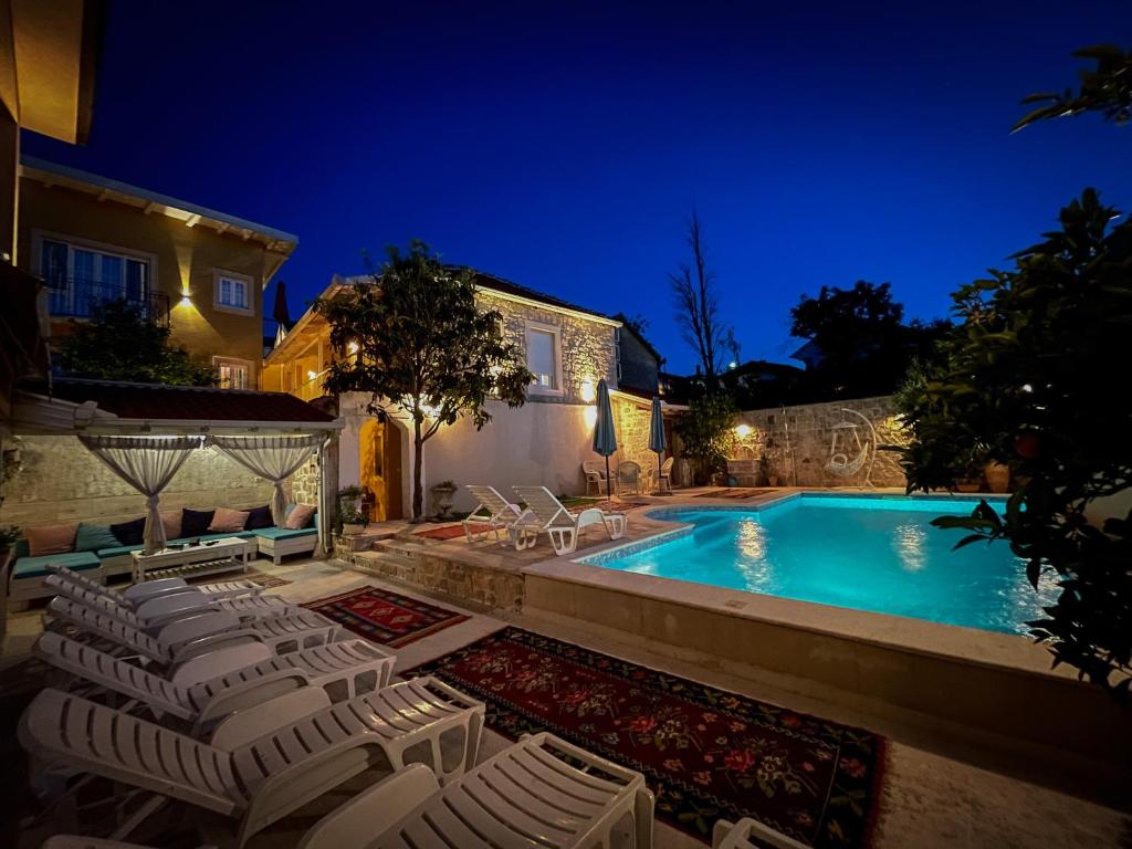 a swimming pool with lounge chairs next to a house at Apartments Villa Mike in Mostar