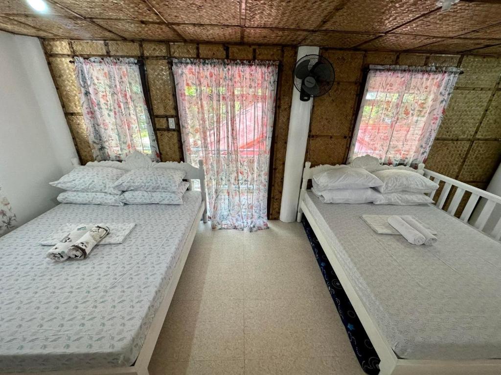 2 camas en una habitación pequeña con ventanas en Lorenza 2 and 3, en Buruanga
