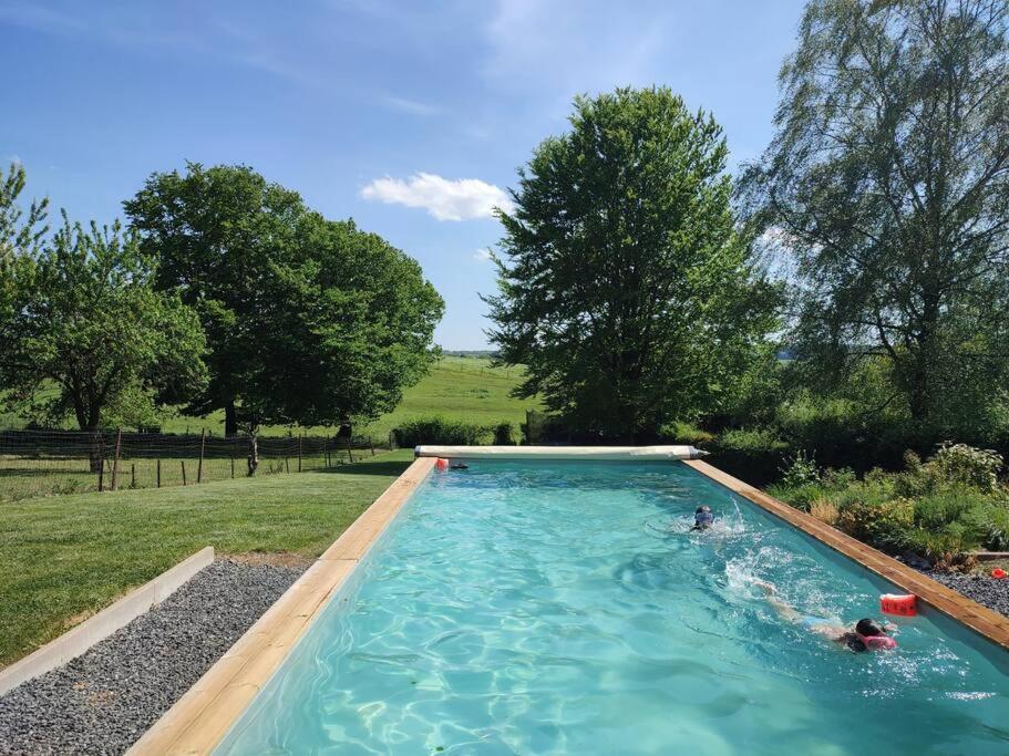 una piscina con 2 personas en el agua en Le Floyon (avec piscine), en Florennes