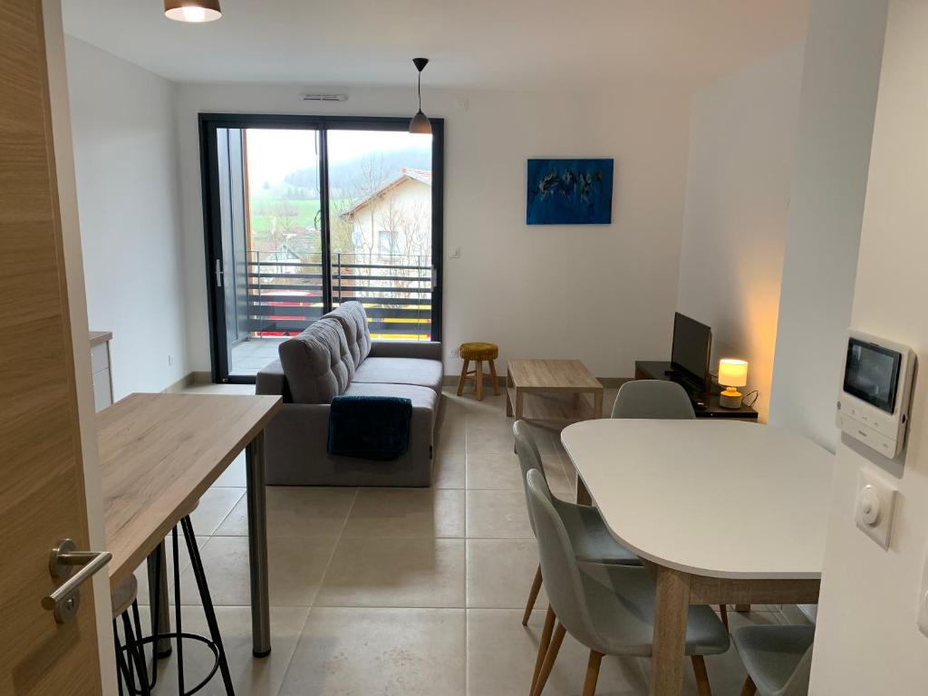 a living room with a white table and a couch at Appartement neuf en cœur de station in Métabief