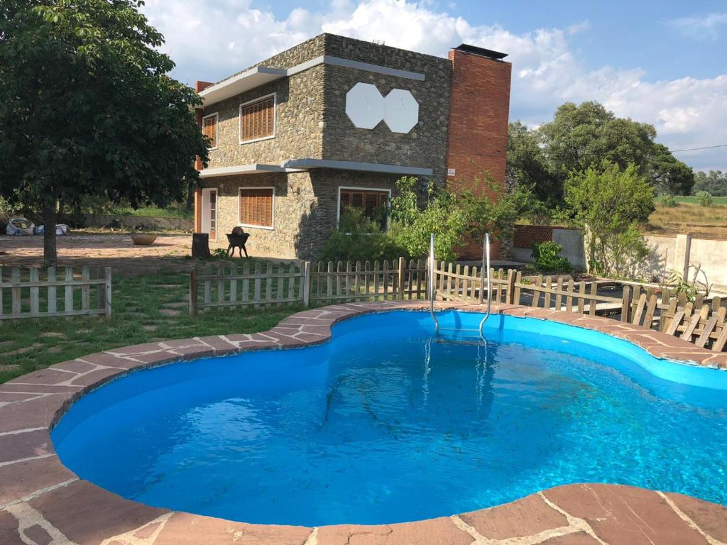 Una piscina frente a una casa con un cartel. en Casa L'Avi, en Plegamans