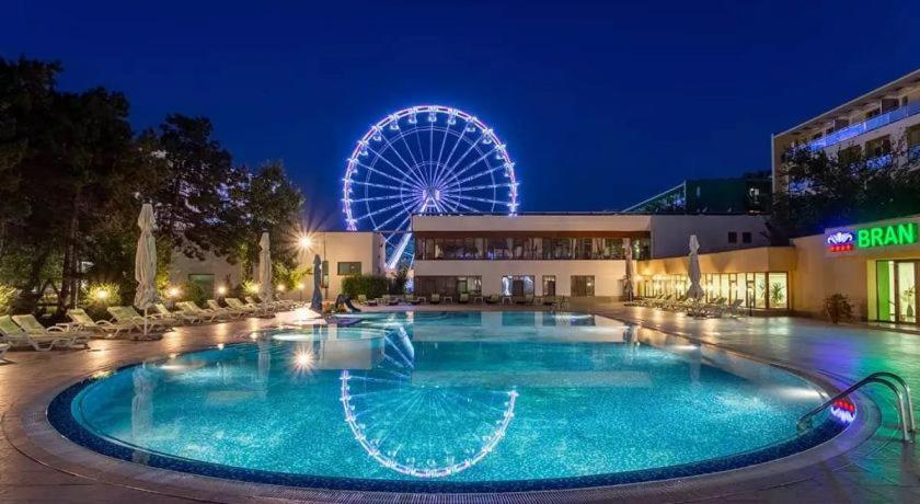 a large swimming pool with a ferris wheel in the background at Bran Brad Bega by Steaua de Mare in Eforie Nord