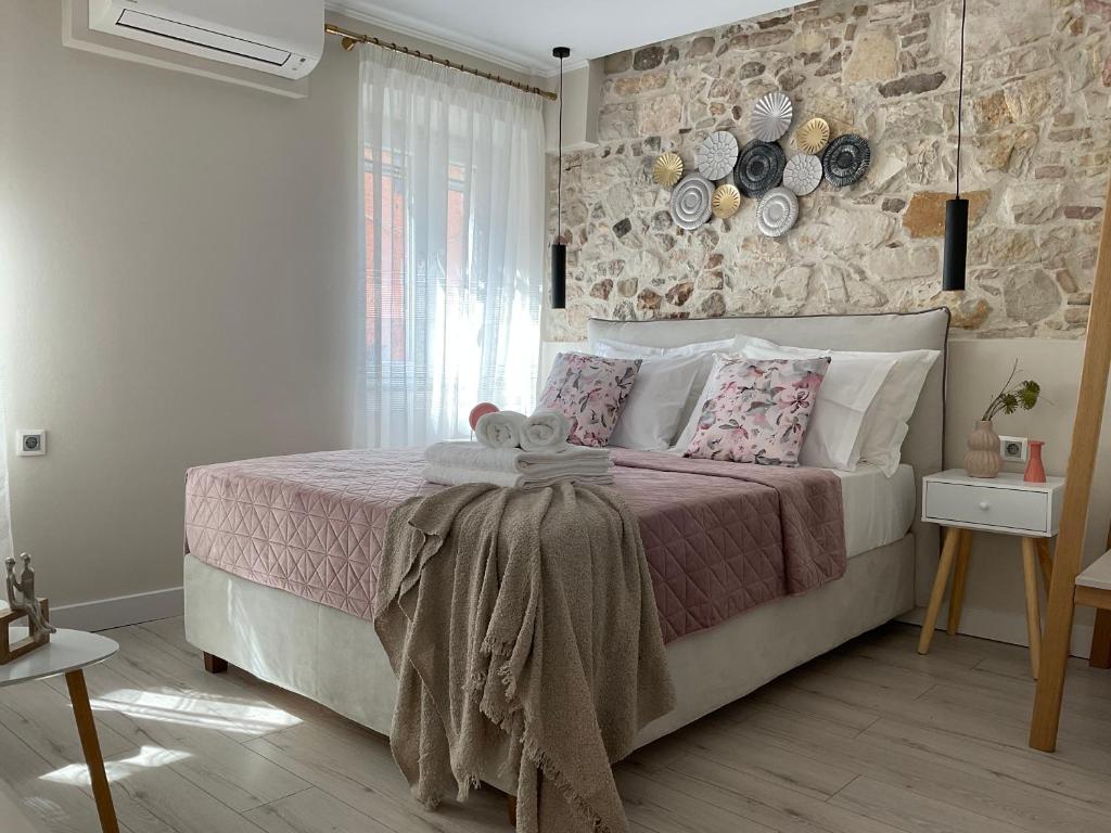 a bedroom with a large bed with a stone wall at Biscoutsis old town studio in Corfu