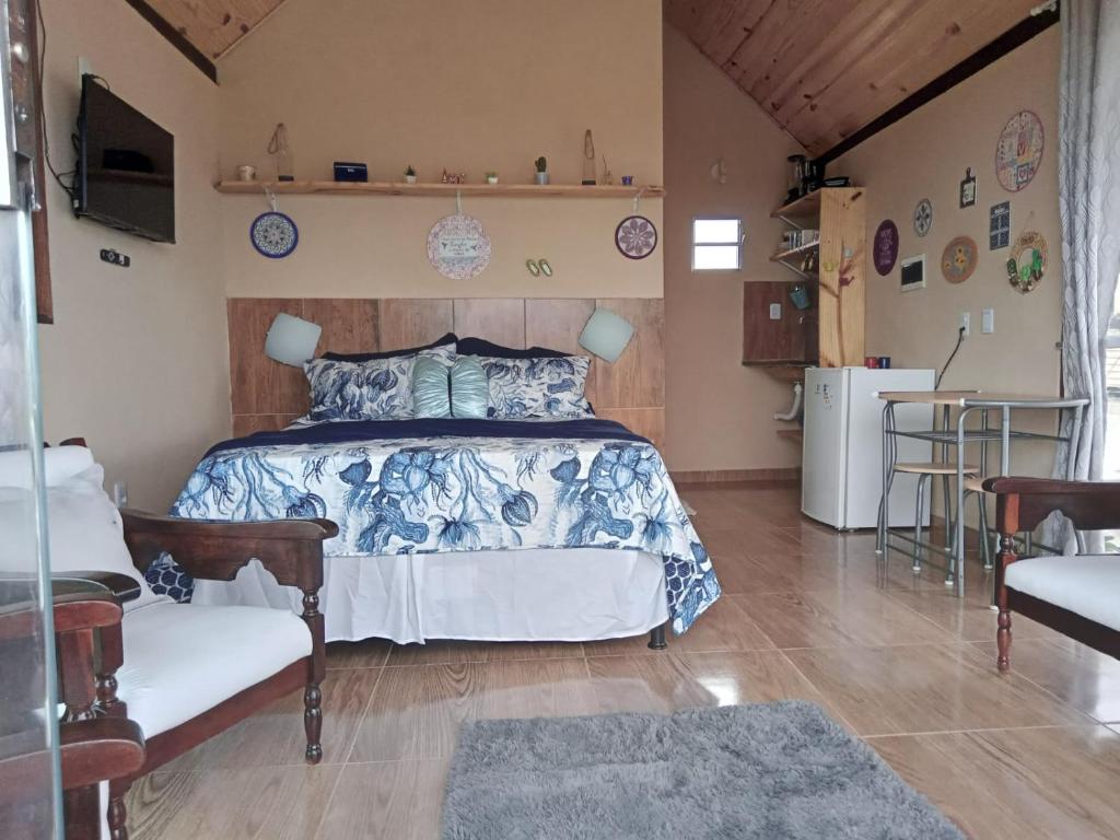 a bedroom with a bed and a couch and a table at Chalé Mirante da Pedra in Serra de São Bento