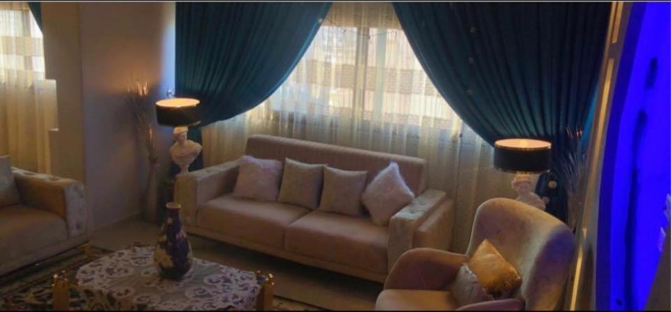 sala de estar con sofá, sillas y cortinas azules en شقة مفروشة هاى سوبر لوكس بجوار سيتى ستارز, en El Cairo