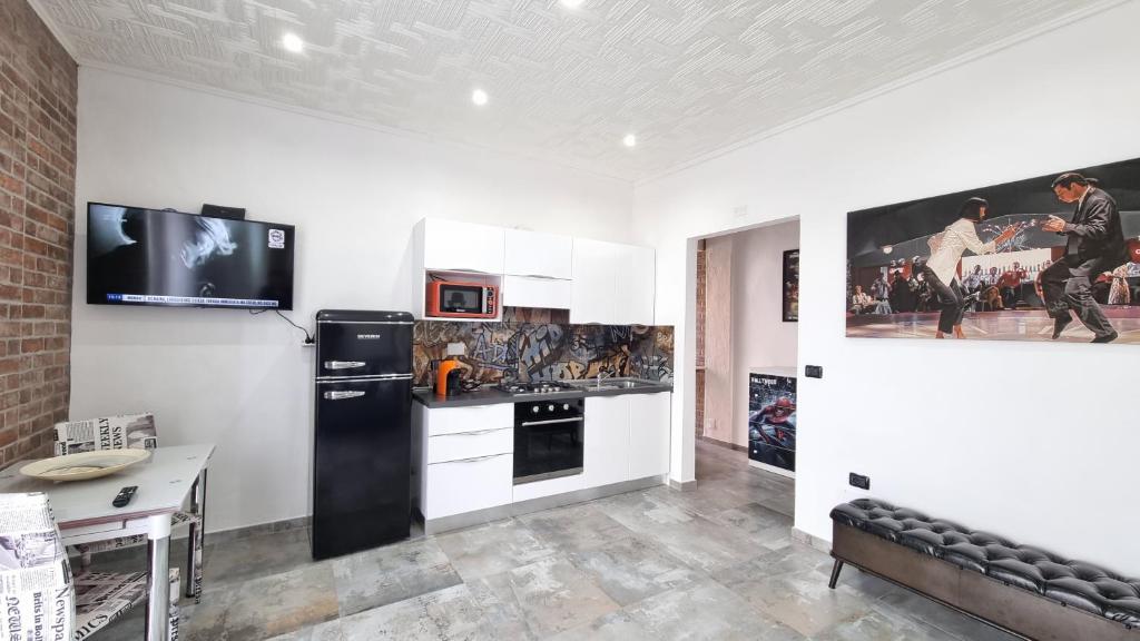 a kitchen with a black refrigerator and a tv on the wall at Hollywood Apartment in Capoliveri