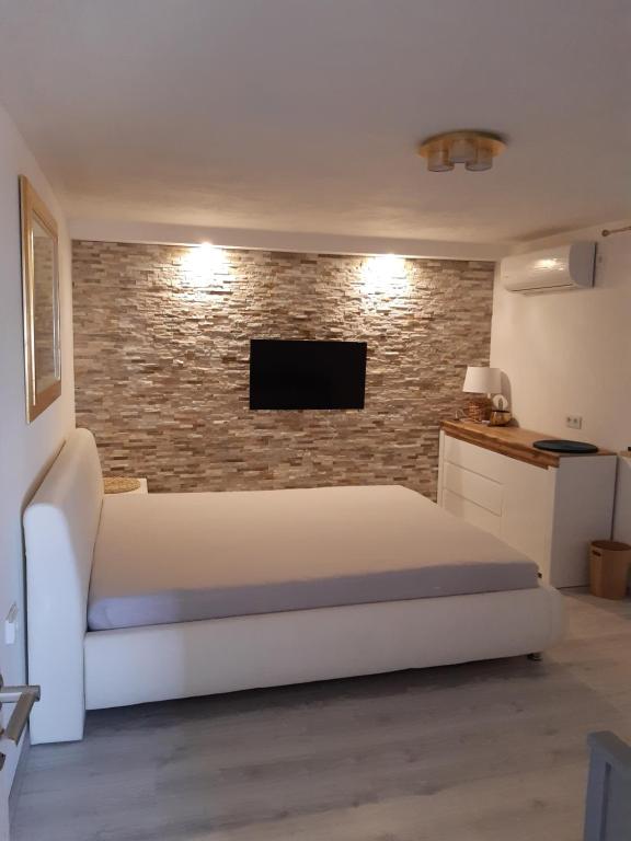 1 dormitorio con cama blanca y pared de ladrillo en Apartment Ena, en Stara Novalja