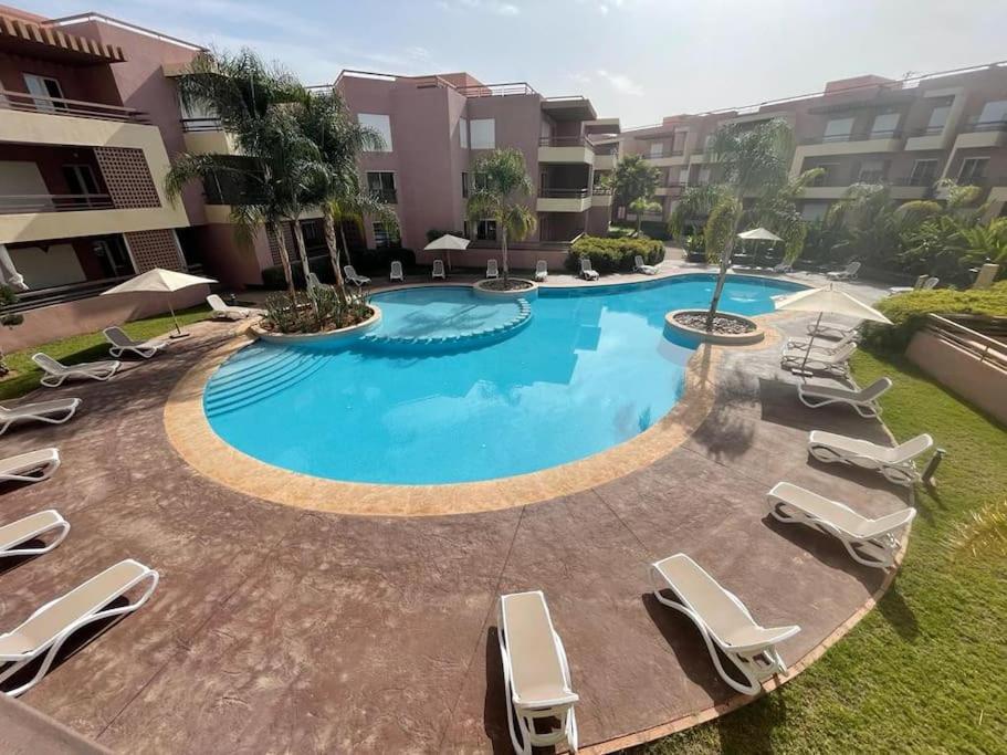 uma grande piscina com espreguiçadeiras num pátio em Magnifique appartement à Riad Garden em Marrakech