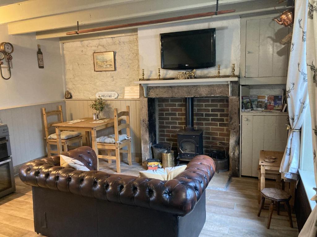 un salon avec un canapé en cuir et une cheminée dans l'établissement Willow Cottage, à Middleton in Teesdale