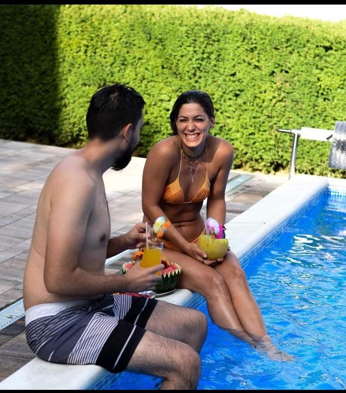 a man and a woman sitting next to a swimming pool at Apartmani Breza in Vrdnik