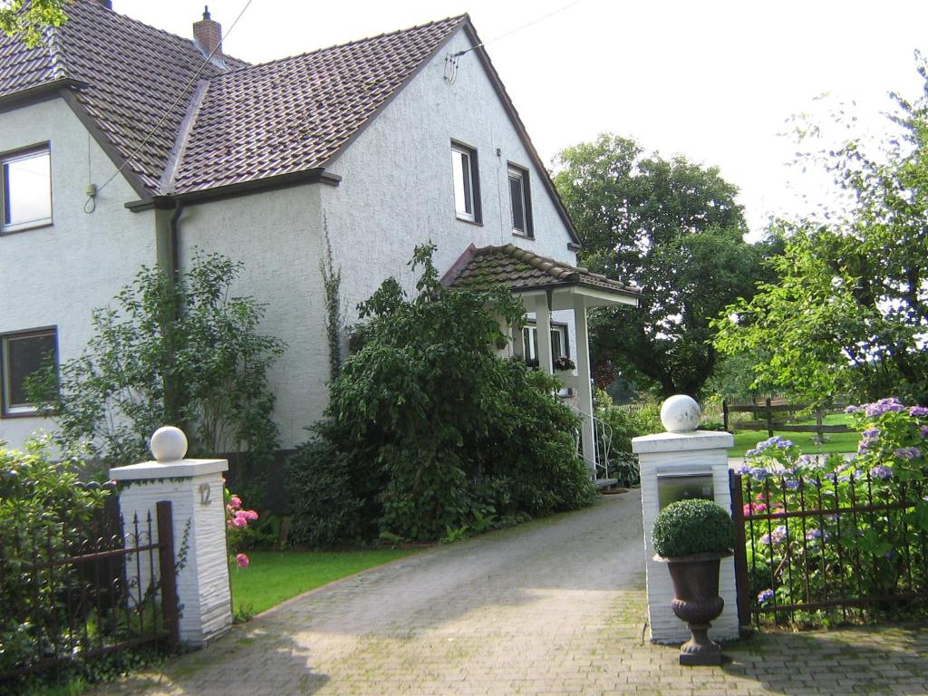 ein weißes Haus mit einem Tor und einer Einfahrt in der Unterkunft Ferienwohnung am Reiherbach in Bielefeld