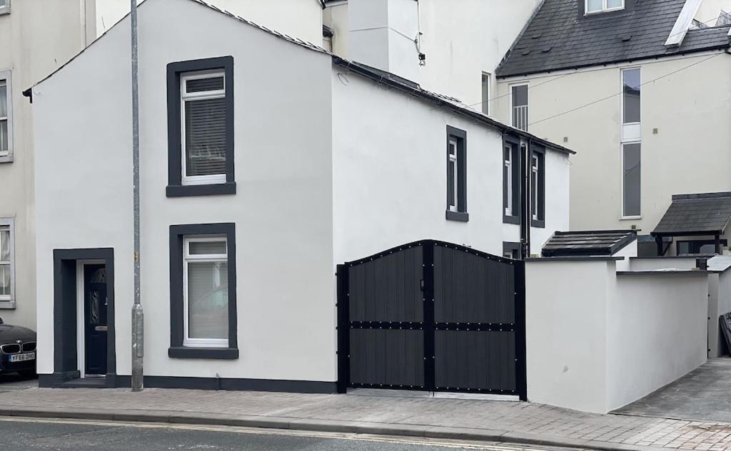 a white house with a black gate on a street at Quirky cottage in the centre of Penrith with a Hot Tub in Penrith
