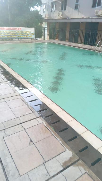 a swimming pool with blue water in a building at Eastpark Apartment in Jakarta
