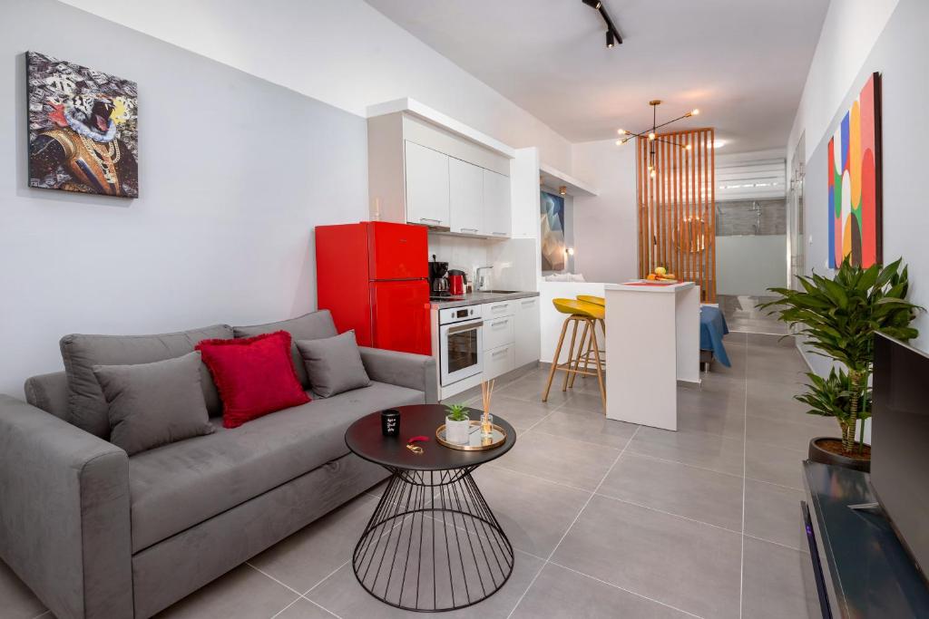 a living room with a couch and a table and a kitchen at Theo's Cozy Apartment near Athens airport in Spata