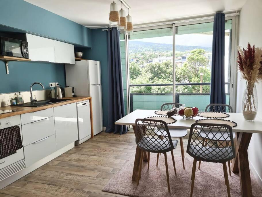 une cuisine avec une table et des chaises ainsi qu'une grande fenêtre dans l'établissement Studio56 - Logement Design et Cosy à Etang Salé, à L'Étang-Salé