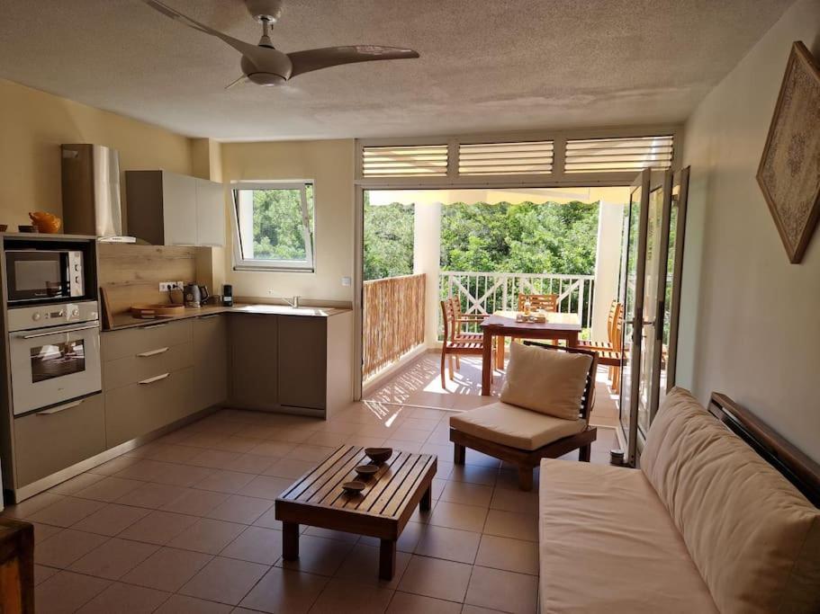 a kitchen and living room with a couch and a table at Joli Duplex 6 pers. avec piscine in Le Diamant