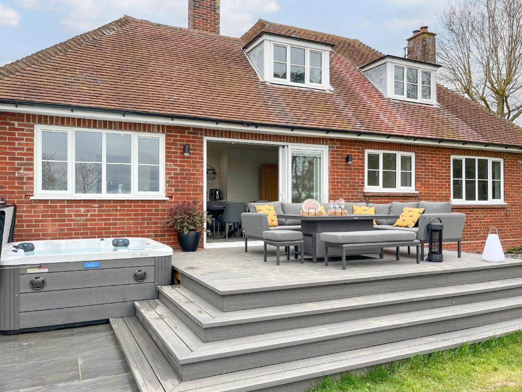 a wooden deck with a hot tub and a house at Longridge in Peldon