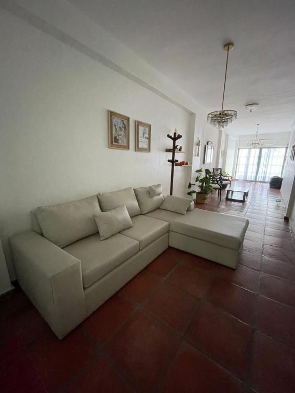 uma sala de estar com um sofá branco e piso em azulejo em Casa Evaluna em San Pedro