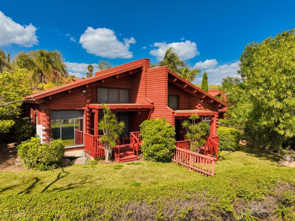 Ein Harod Country Lodge في ‘En H̱arod: منزل خشبي مع سطح وأشجار