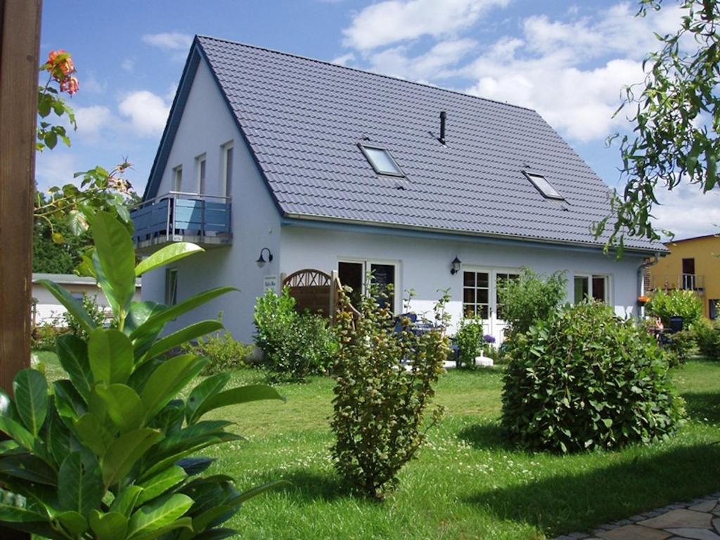 una casa blanca con techo de gambrel en Apartment Käpt'n Max, en Ostseebad Karlshagen