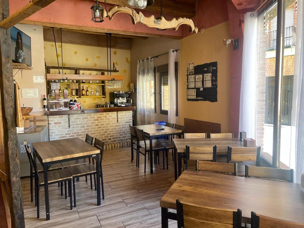 um restaurante com mesas e cadeiras de madeira e um bar em Albergue hostal Sahagún em Sahagún