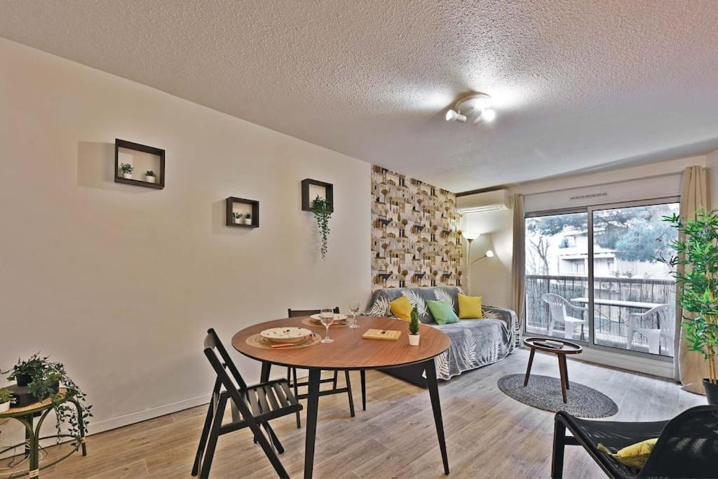 un salon avec une table et un canapé dans l'établissement Les Comtadins - PARKING Gratuit - Balcon - Clim, à Avignon