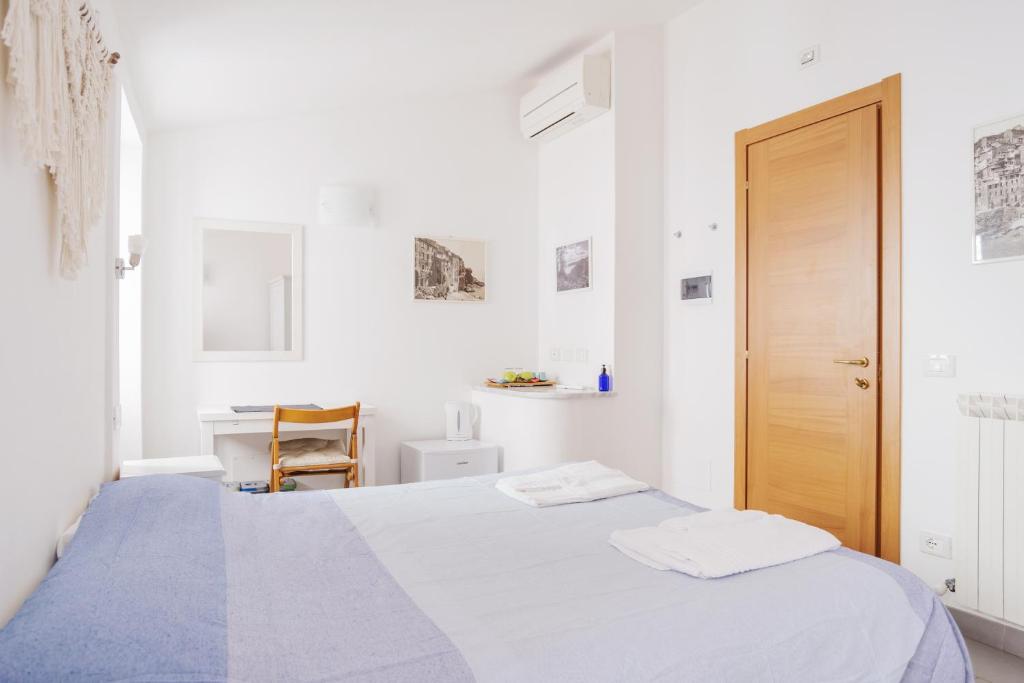 a white bedroom with a bed and a desk at Banchi in Riomaggiore