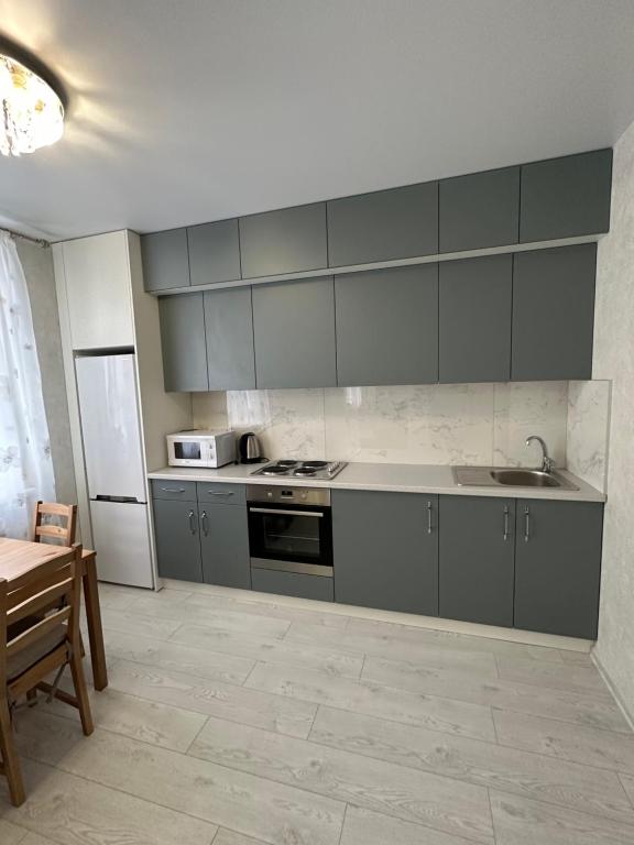 uma cozinha com armários cinzentos, um lavatório e uma mesa em Sky apartments Budova em Odessa