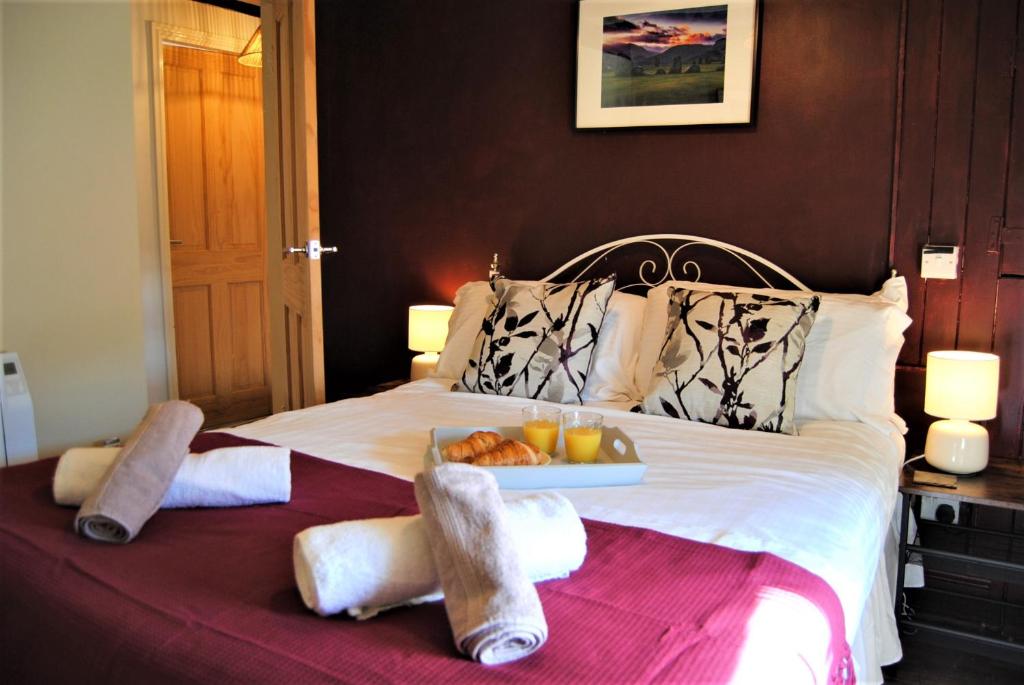 Una cama con toallas y una bandeja de comida. en Snowdon Cottage 2, en Llanrug