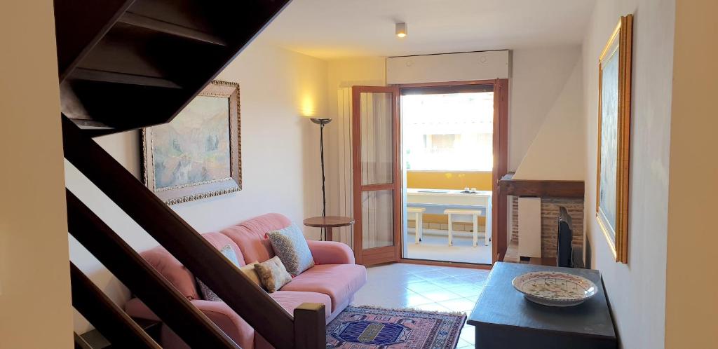 uma sala de estar com um sofá rosa e uma mesa em Charming apartment & parking by ANTHEA HOMES em Grado