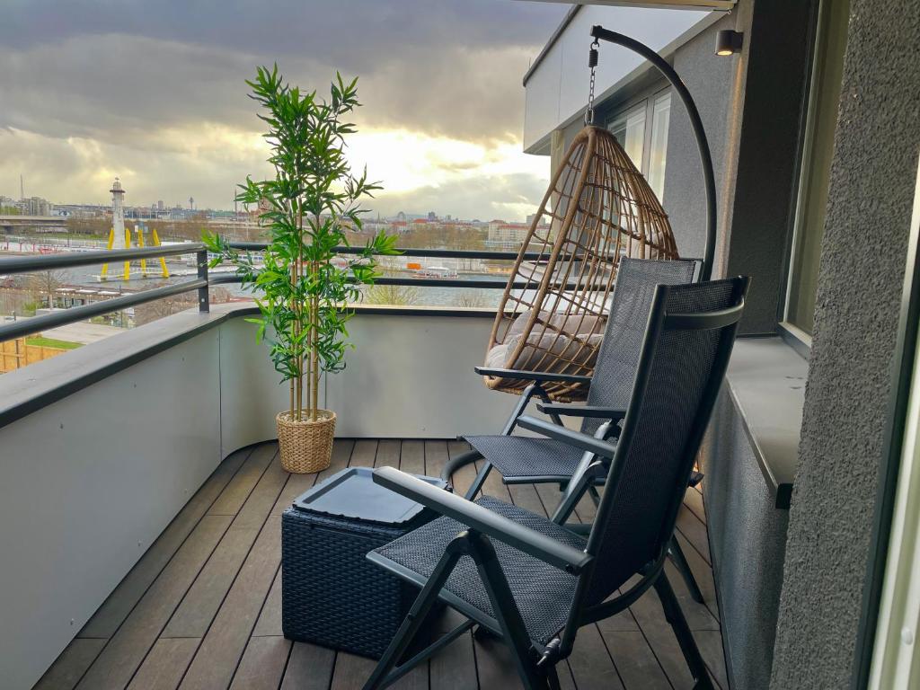 a balcony with two chairs and a swing at Riverfront Apartment with Balcony and AC in Vienna