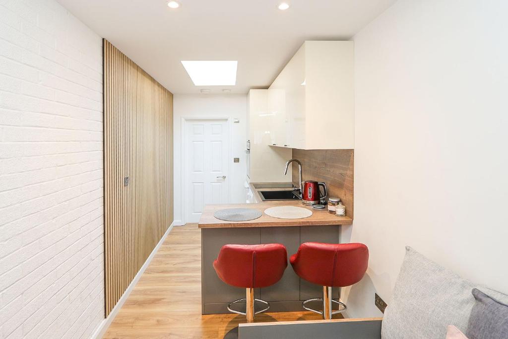 uma cozinha com duas cadeiras vermelhas e um balcão em Peaceful and Novel Place to Stay em Abbey Wood
