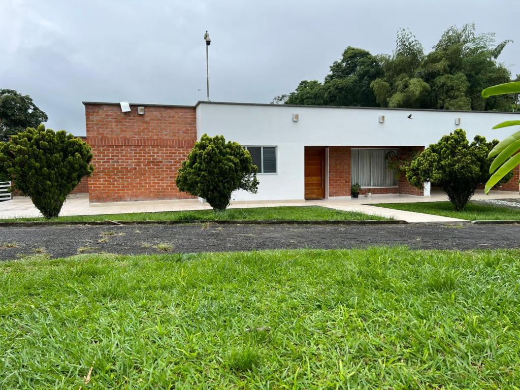 un edificio de ladrillo con árboles delante de él en Casa Campestre Sol Naciente, en La Tebaida