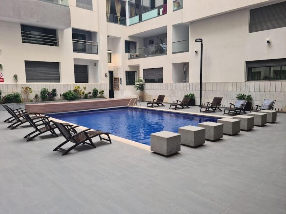 een zwembad met stoelen en een gebouw bij luxe appartement met zeezicht en zwembad Mohammedia Parc in Mohammedia