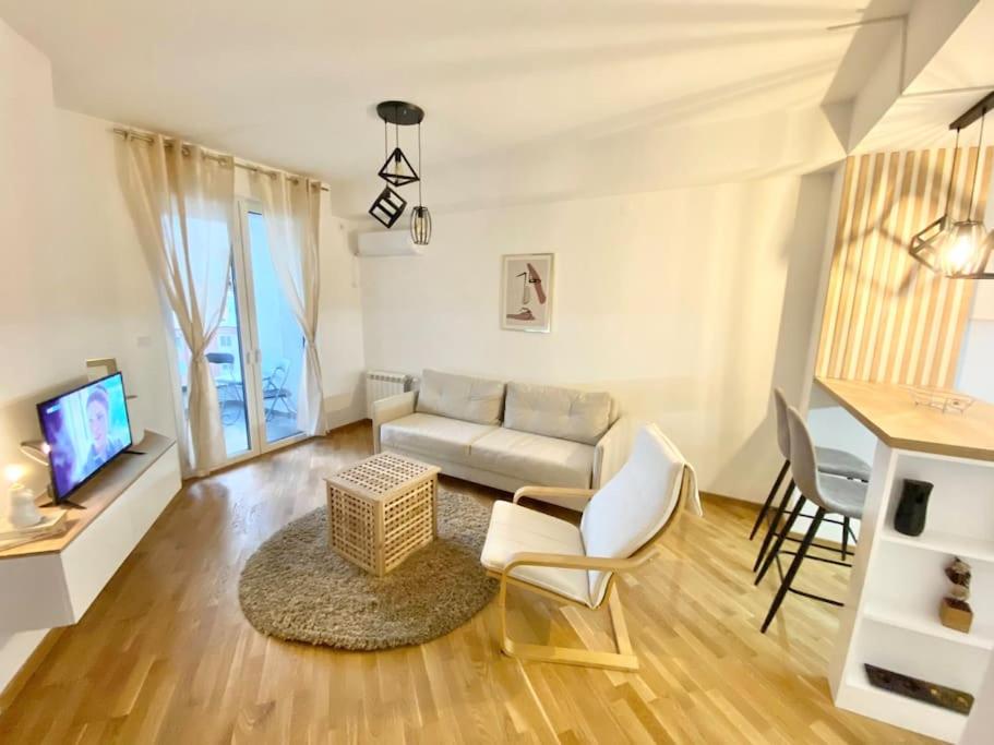 a living room with a couch and chairs and a tv at Bright Scandi Apartment in Skopje